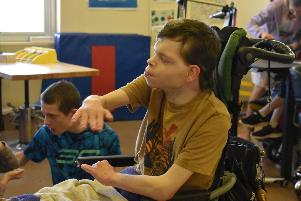 A student hanging out in his classroom while other students are in the background