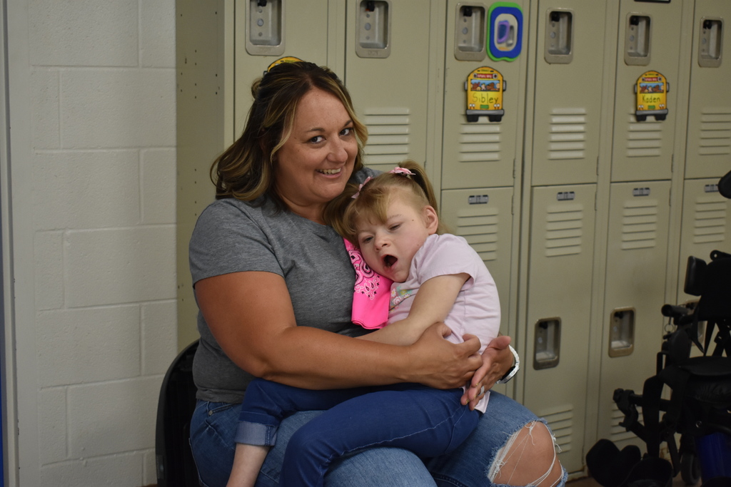 A teacher holding a student on her lap as both smile