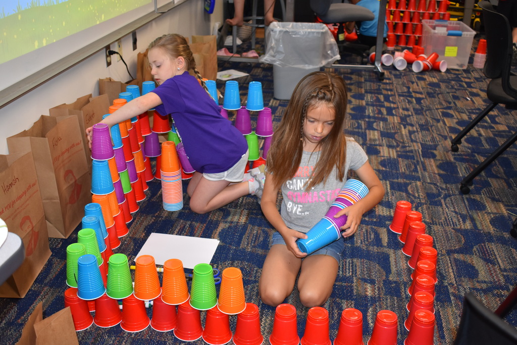 Two young kids stacking cups in a giant square