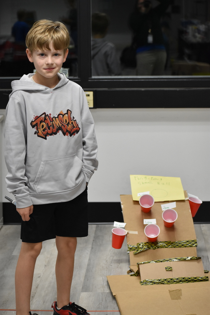 A kid standing next to the game he made