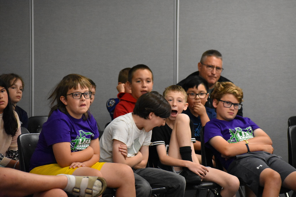 A crowd photo where kids are making wild faces at the science experiment they just witnessed