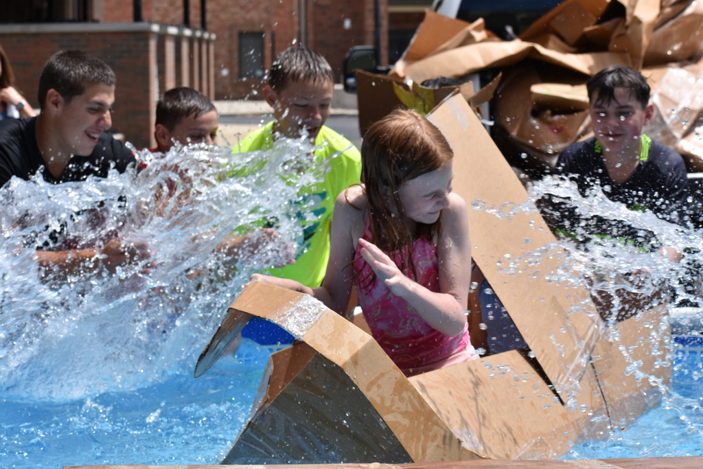 Two students trying out their bus while others splash water into the boat