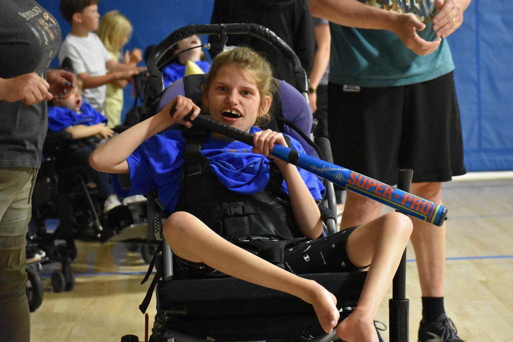 A student in a mobility device holding a baseball bat