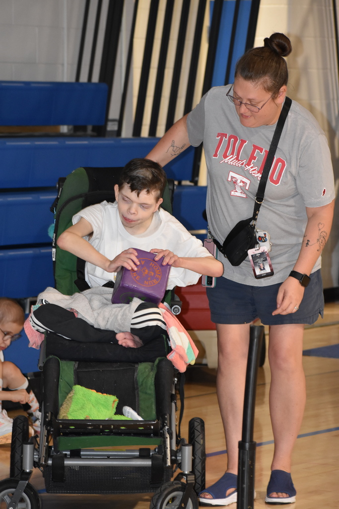 A teacher and a student as the student prepares to throw the cube for adaptive baseball