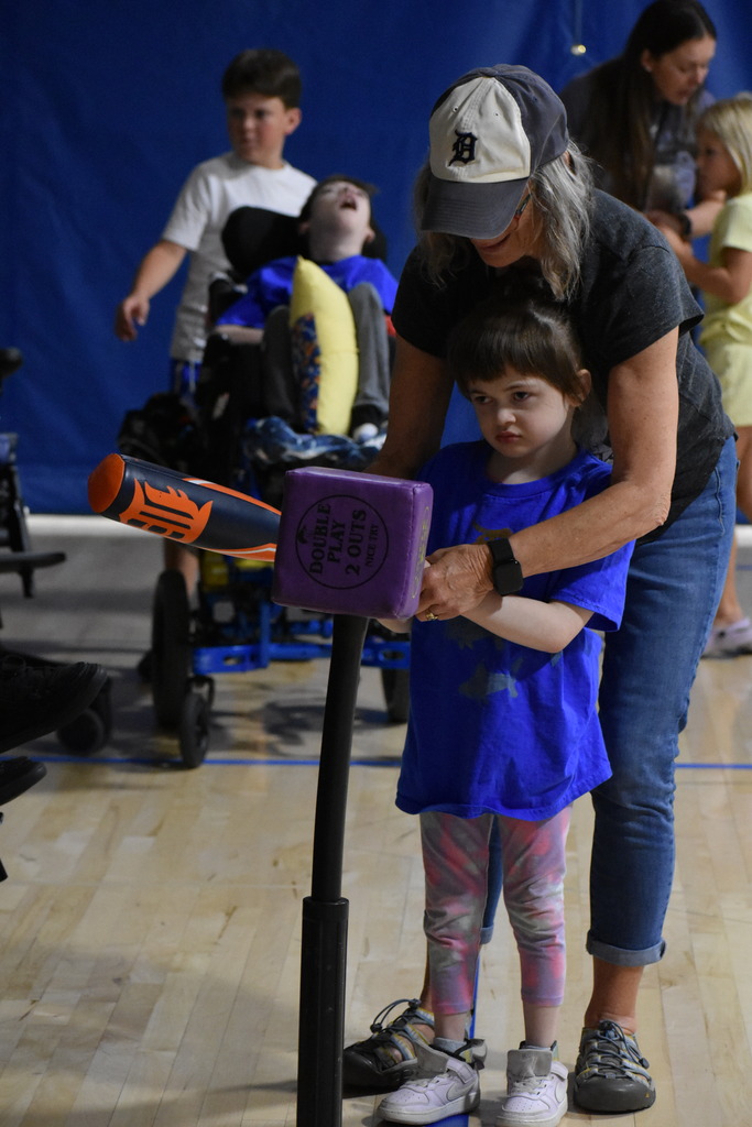 A teacher and young girl hitting the cube off the Tee