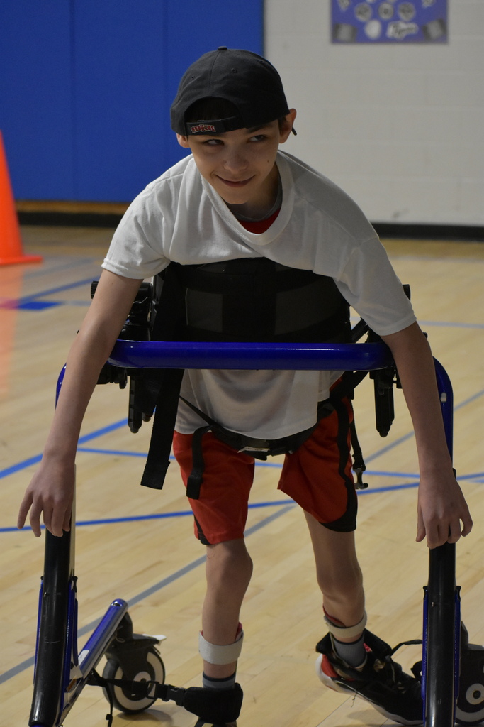 A student walking toward the camera in his walking device while smiling