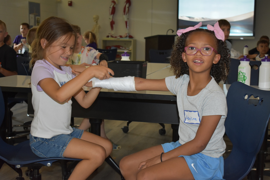 Two young students working together to wrap an arm