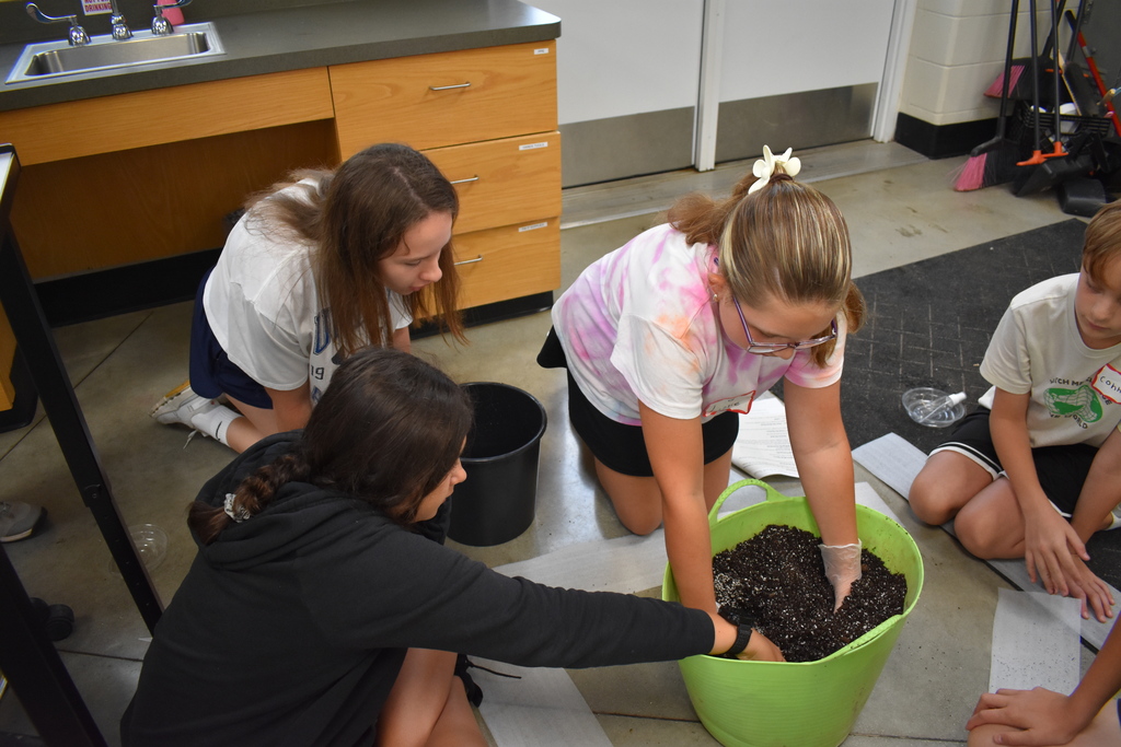 Students working with soil in a bucket