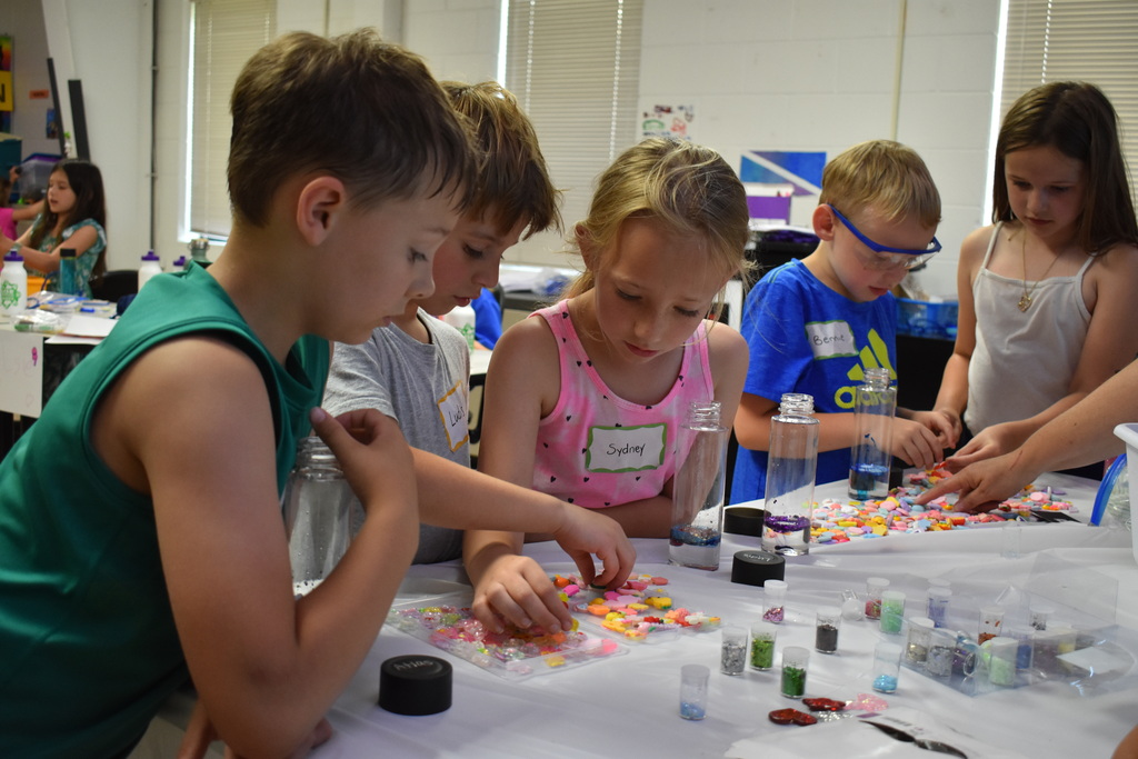 Young students working on an art project and choosing objects from a tray