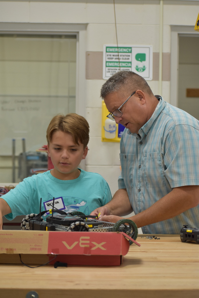 A student working on a robot with the help of a teacher
