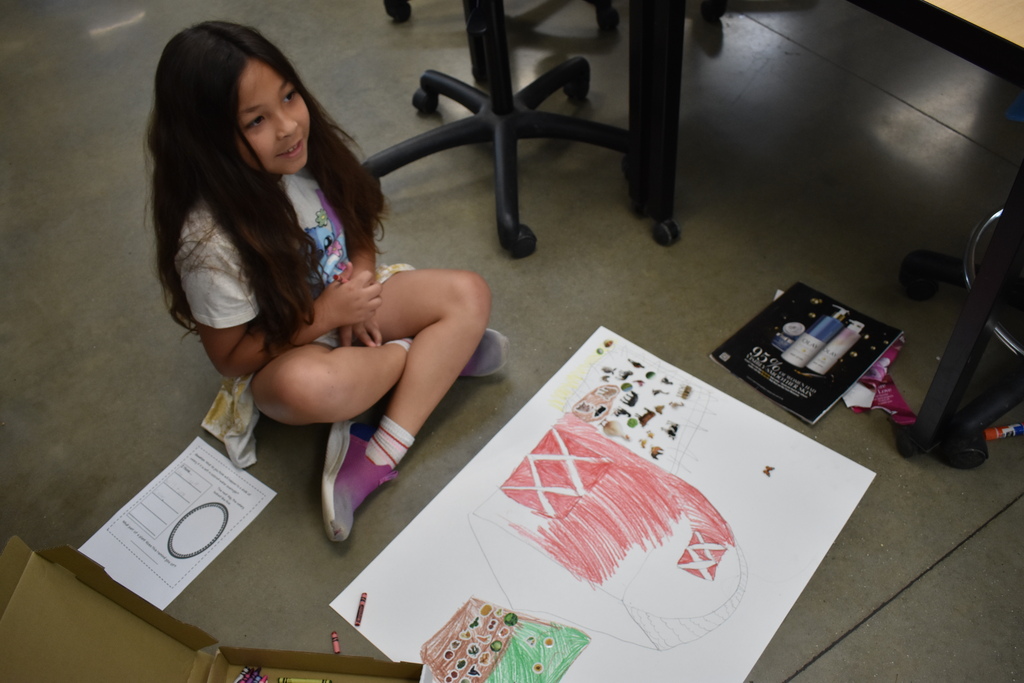 A student with a farm scene that she colored