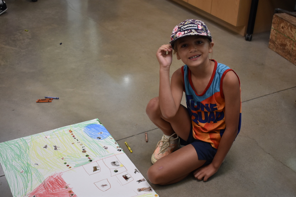 A young student coloring a farm scene on paper