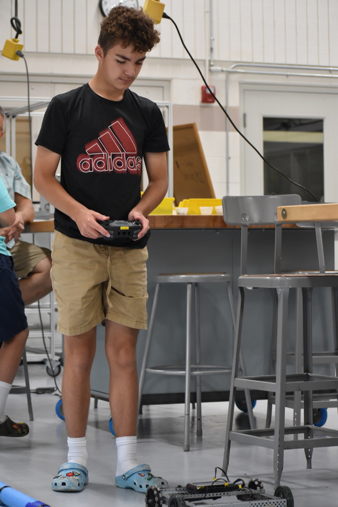 A student with a remote controlling a robot on the ground