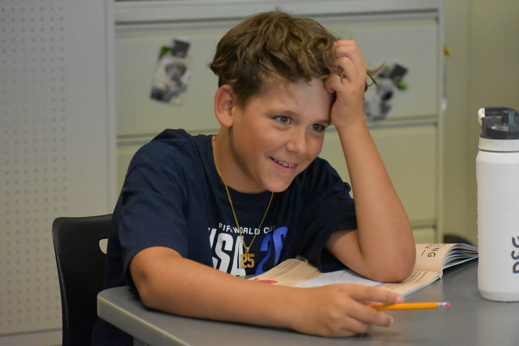 A student smiling and looking across the table at something