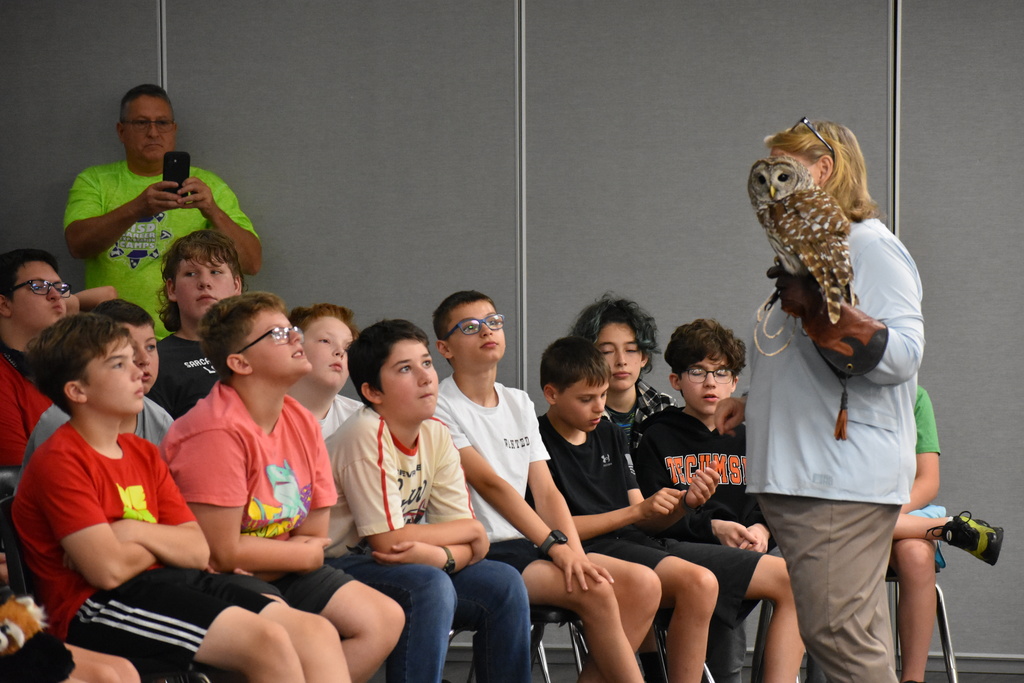Students in a crowd looking at an owl on a presenters arm