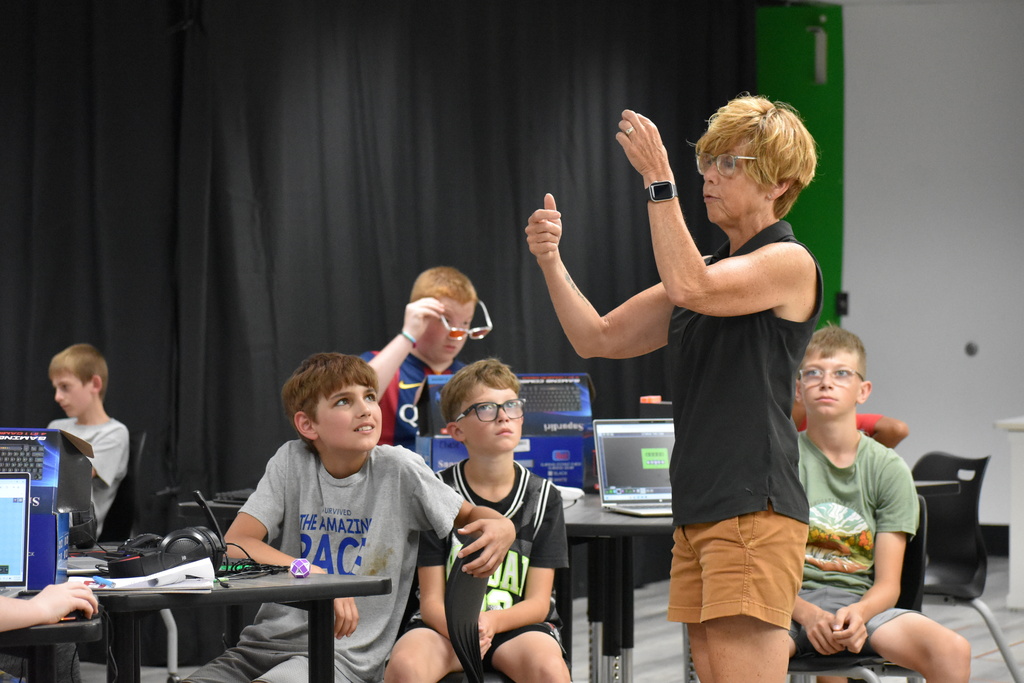 A teacher demonstrating to a class as students look at her