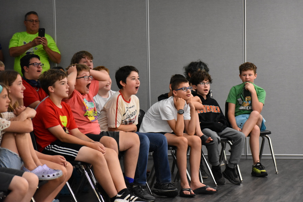 A crowd of kids reacting excitedly to something in front of them