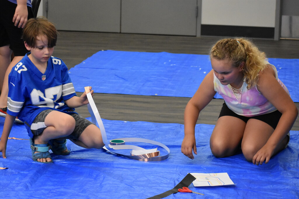 Students on the ground working on a path from their circuitry class