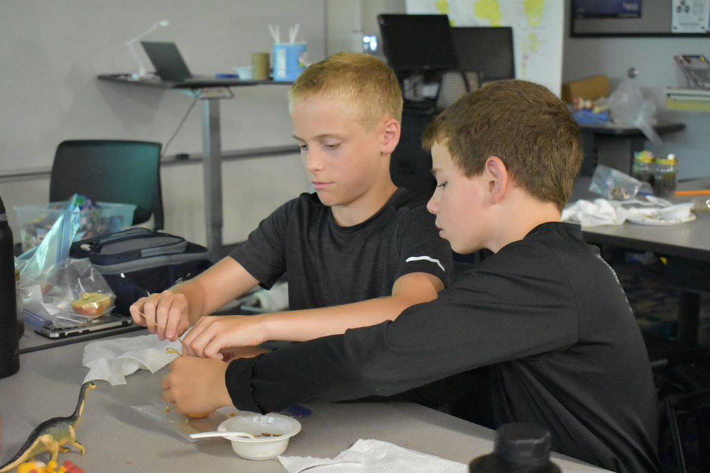 Two students helping each other with bird feeders