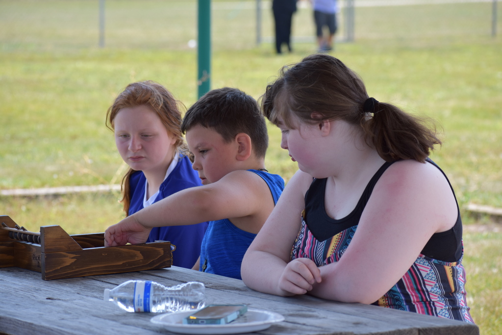 Three students sitting at a picnic table playing a game
