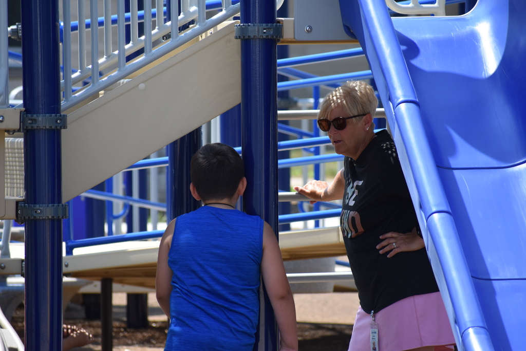 A student and teacher under a playset chatting