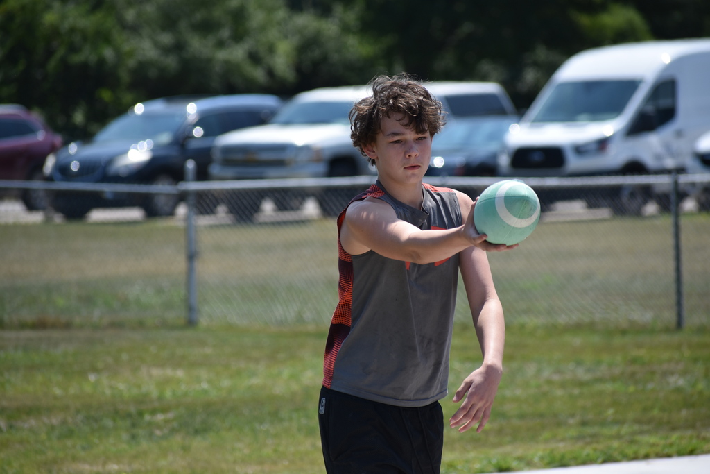 A student holding a ball getting ready to drop kick it on the playground