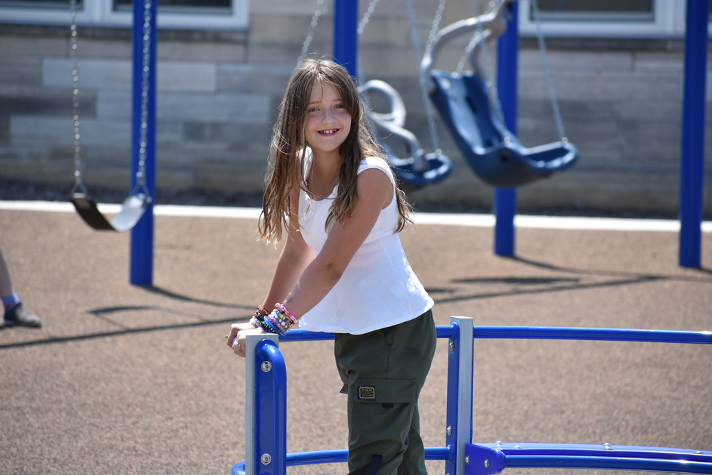 A student smiling as she spins on a piece of playground equipment