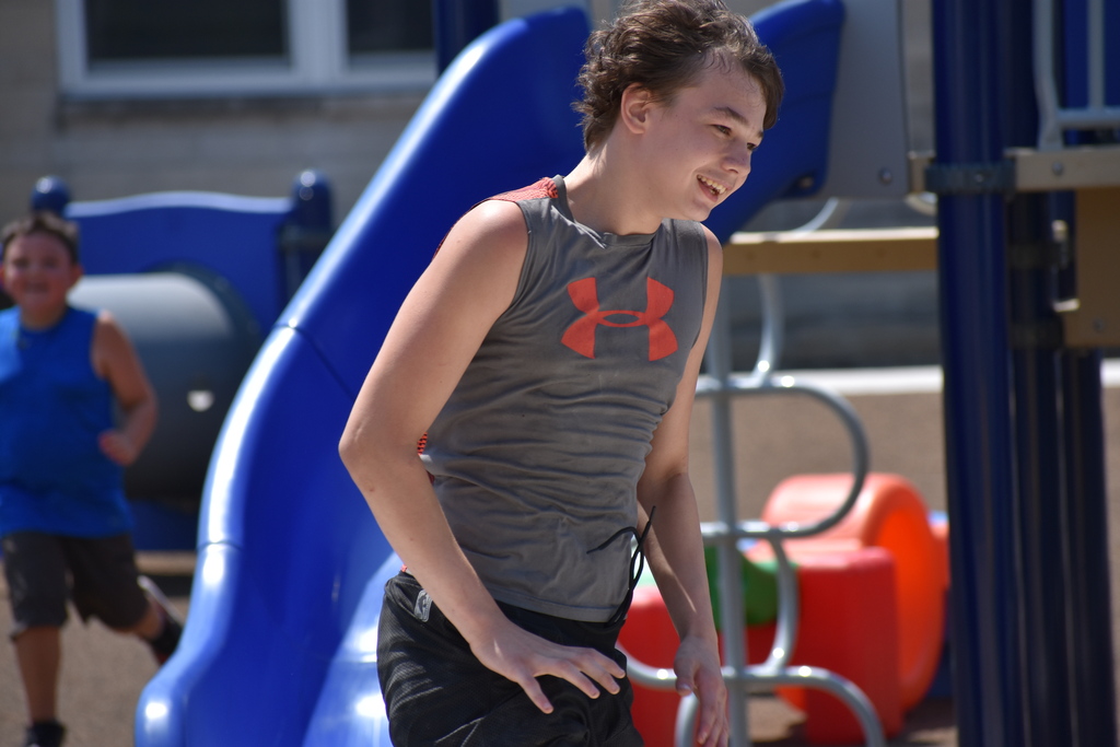 A student running on a playground and smiling 
