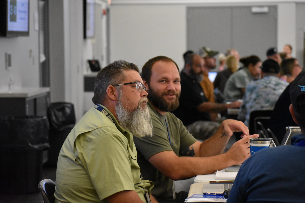 Two LISD teachers seated at their table while one looks at the camera and smiles