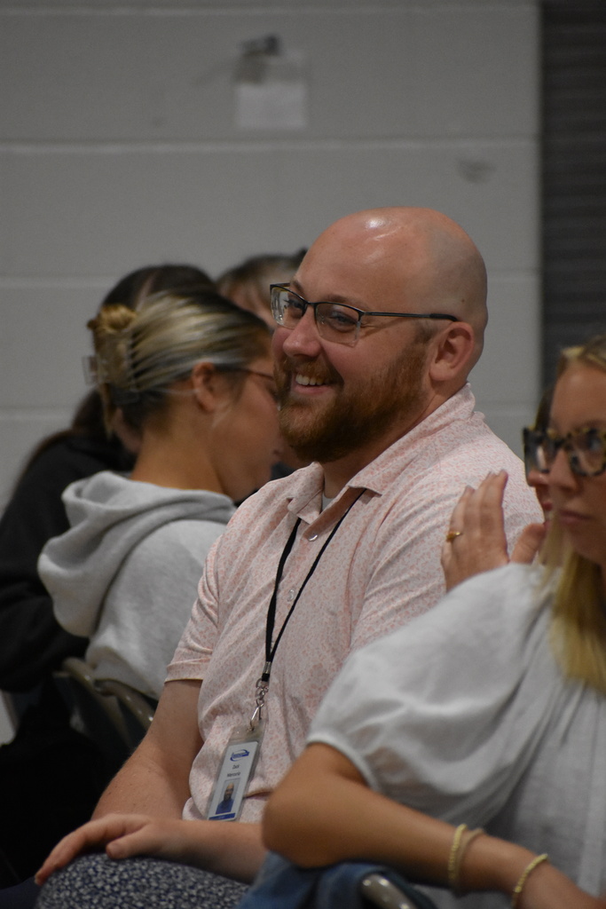 An LISD staff member smiling about something said while seated at his table around his peers