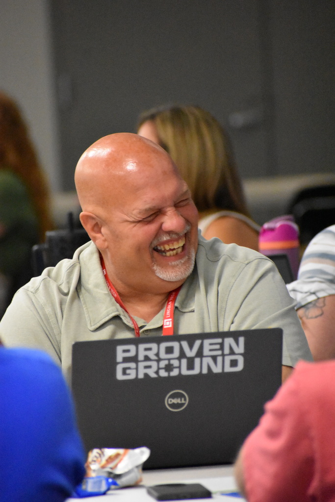 A TECH Center teacher assistant laughing while at his table with his peers