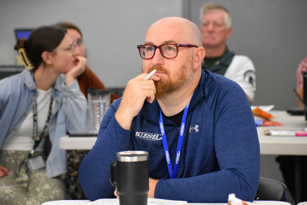 Principal Ben Murray thinking about a question on the board while seated at his table