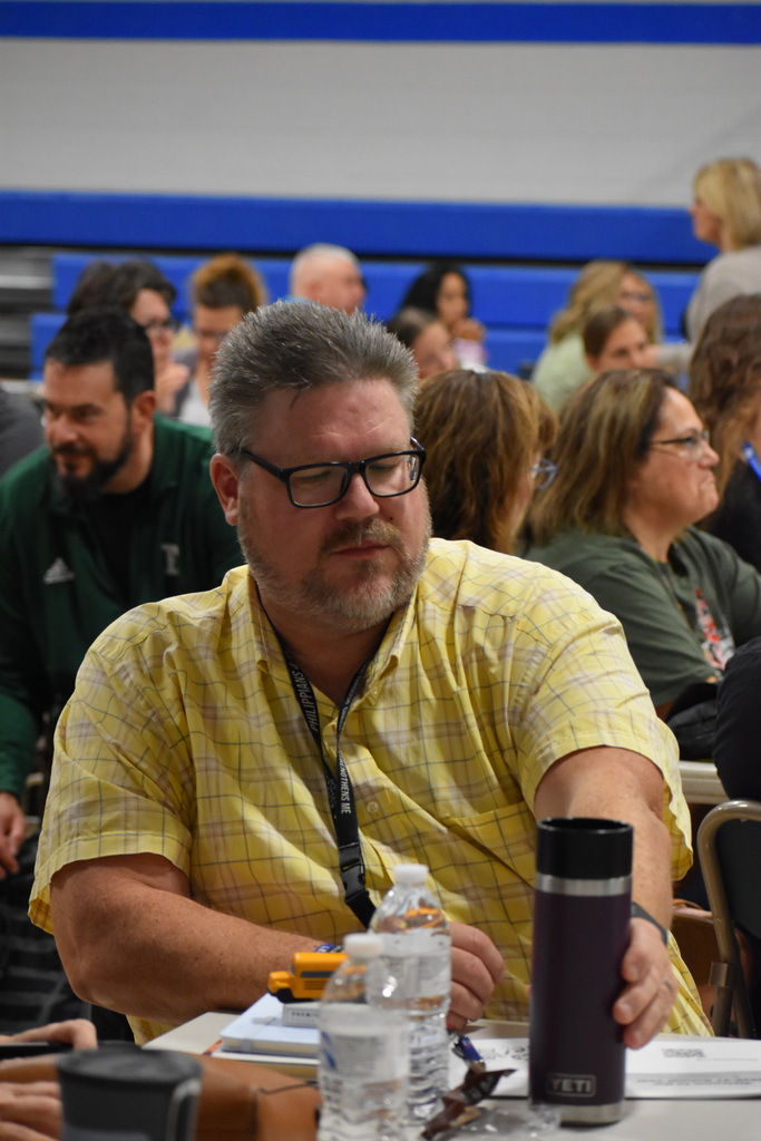 An LISD staff member seated at his table and placing his drink back down