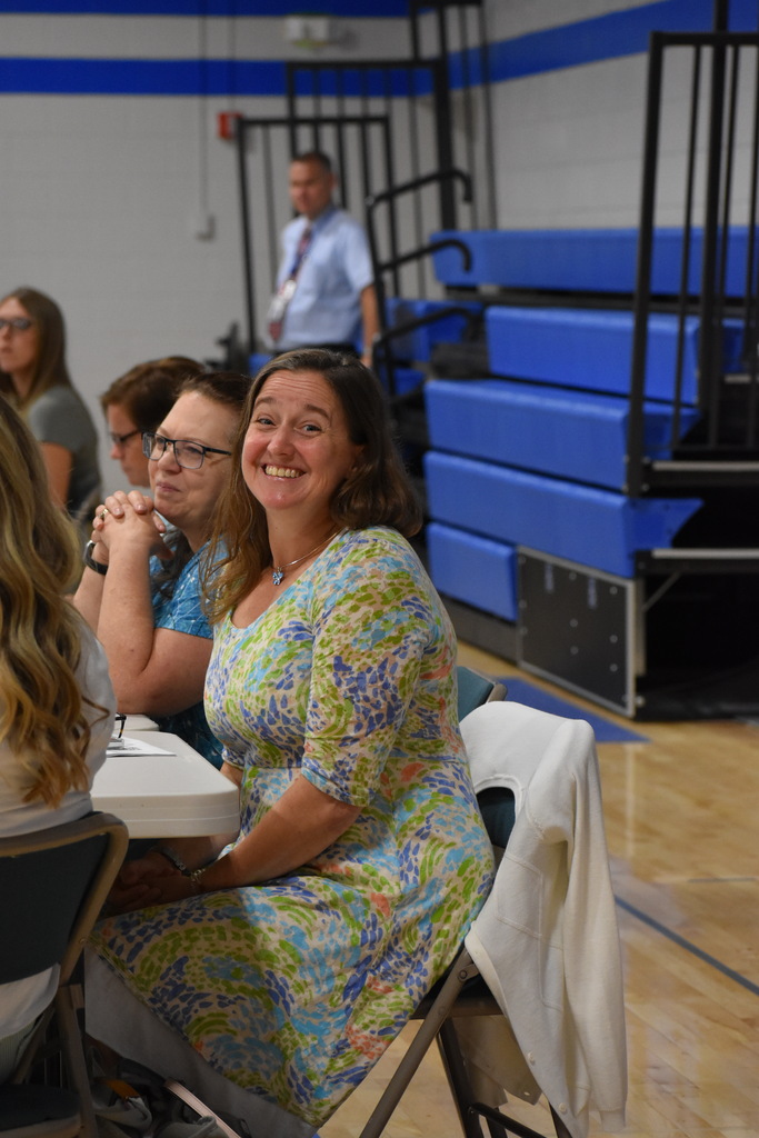 An LISD employee looking at the camera and smiling while seated at her table and others around her look at the presentation