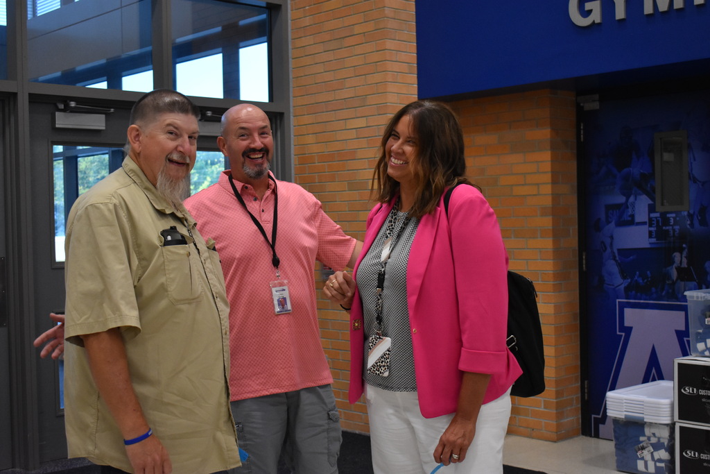 Three people stand together and smile at the camera 