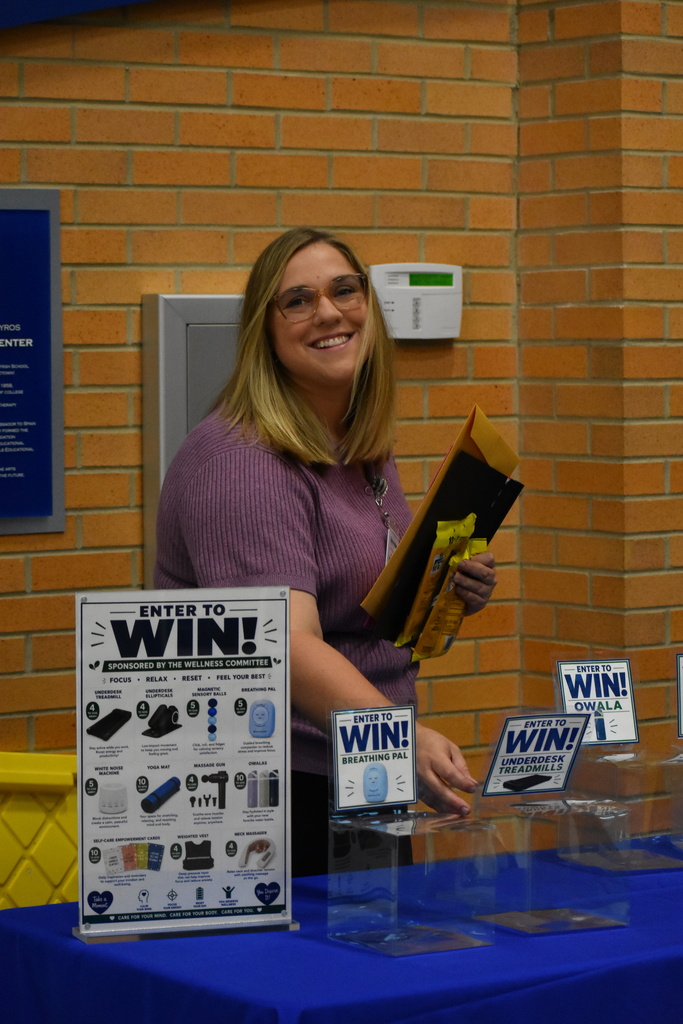 An LISD staff member is organizing a table but stops to smile at the camera