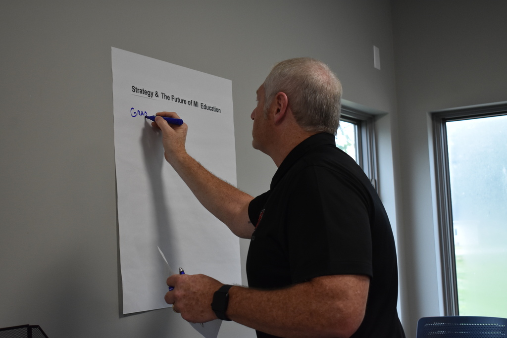 Clinton's superintendent writing on a blank sheet on the wall