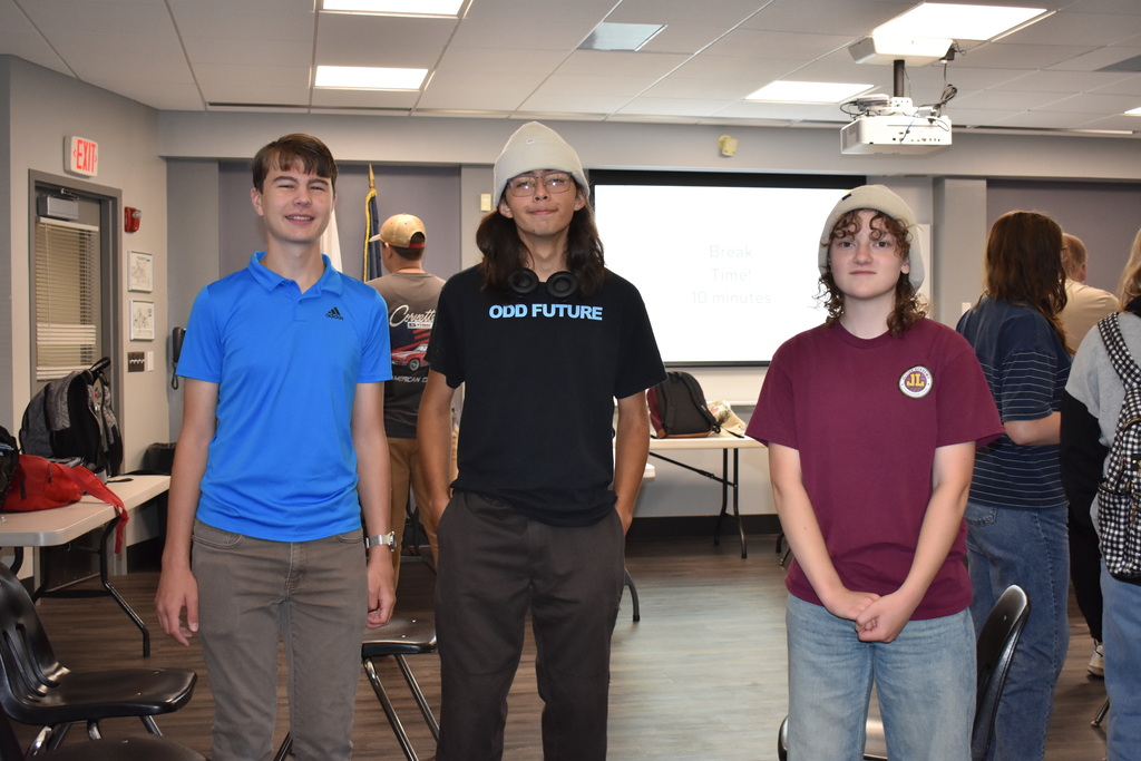 Three students standing and smiling at the camera together