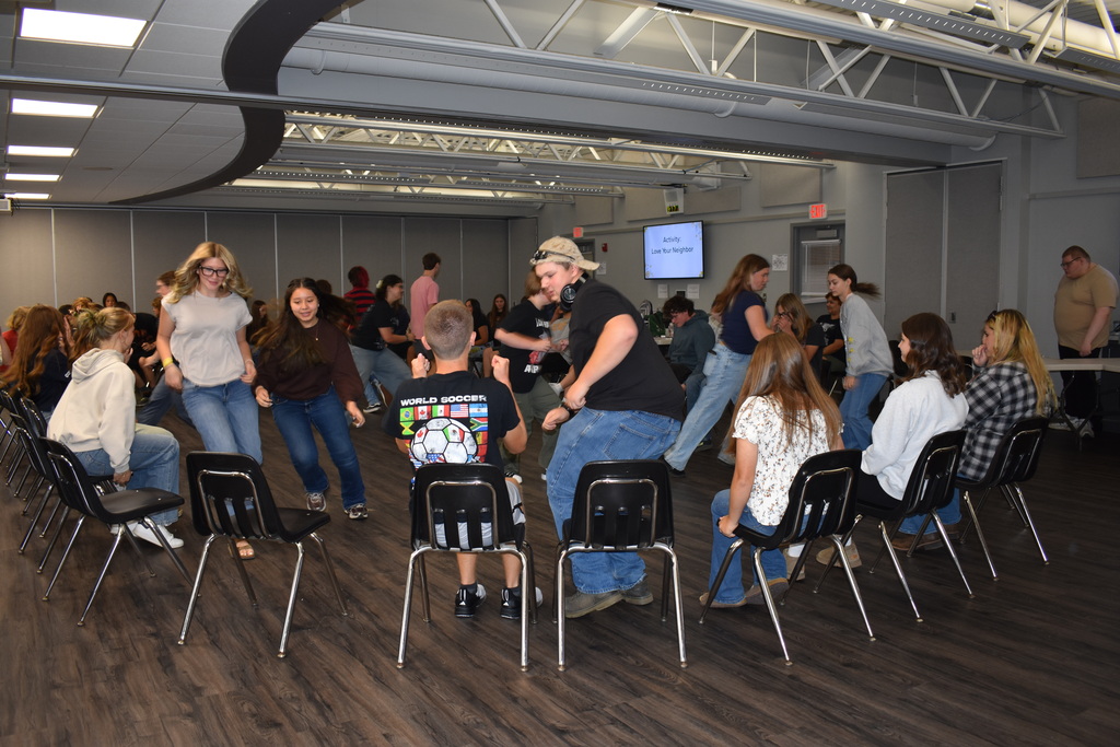 Students running through the middle of the circle to a new seat during a game where everyone is seated in a large circle