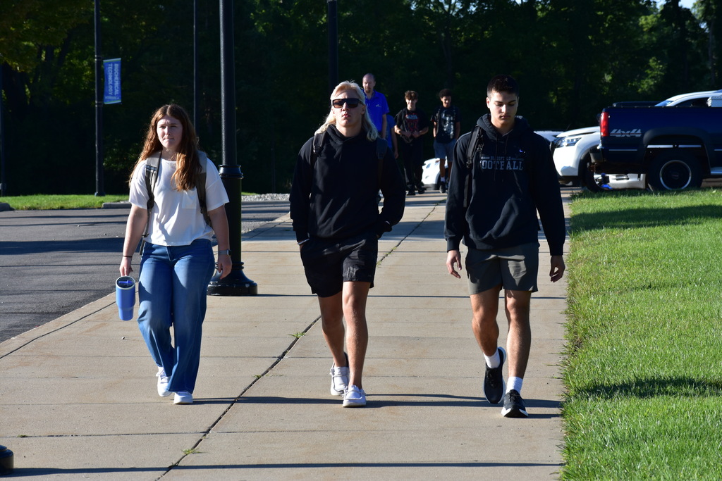 Three students who are friends walking toward the building together