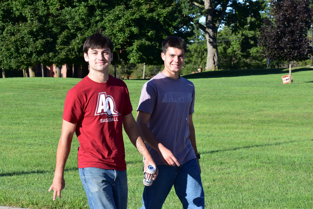 Two students walking outside and both smiling at the camera