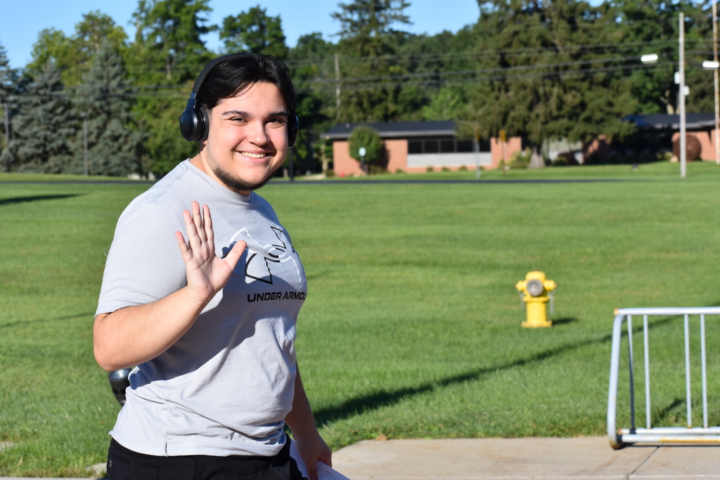 A student smiling and waving at the camera