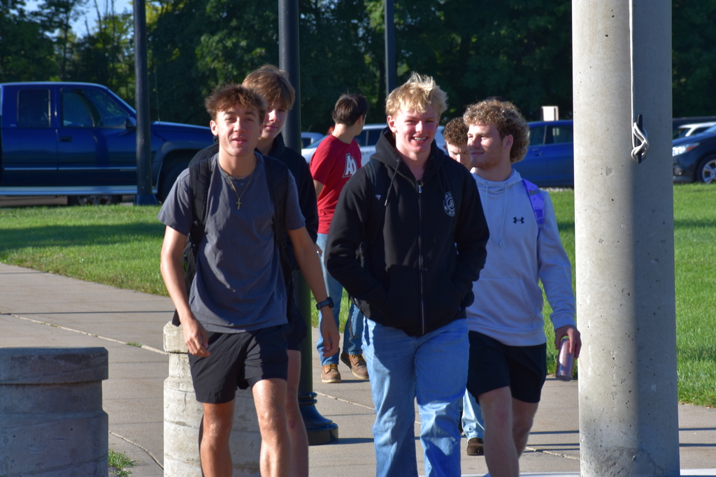 A group of students walking toward the building smiling and chatting together