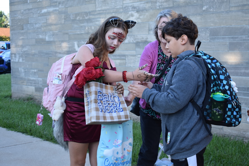 Two students greeting each other as one tries to help take an item from the other's load
