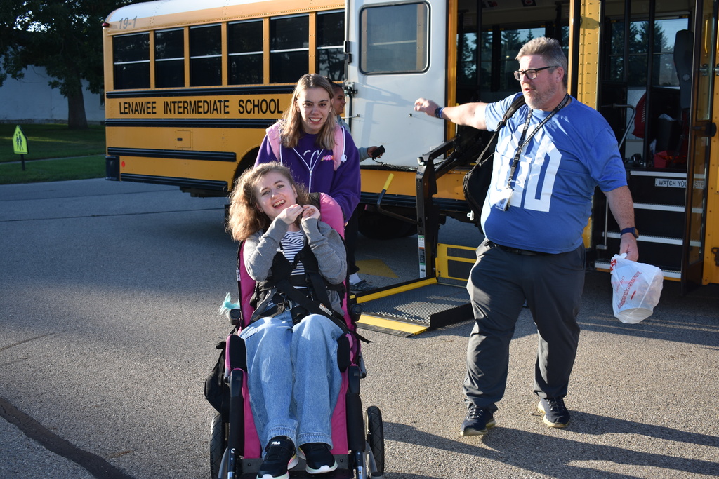 A volunteer, a teacher and a student heading toward the building from the bus