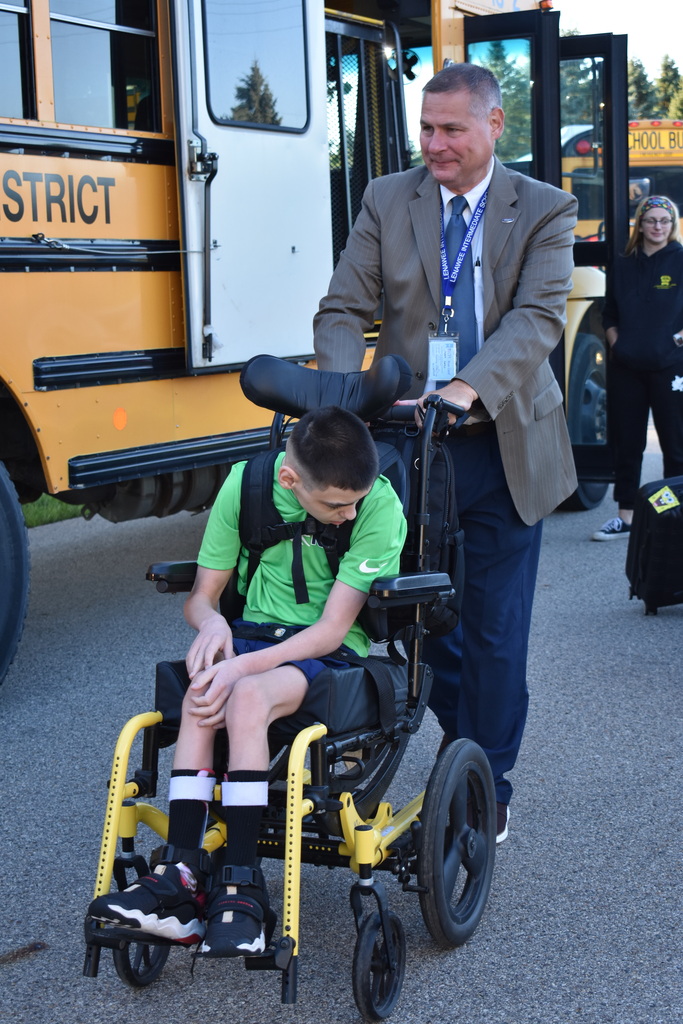 Superintendent Mark Haag wheeling a student toward the building