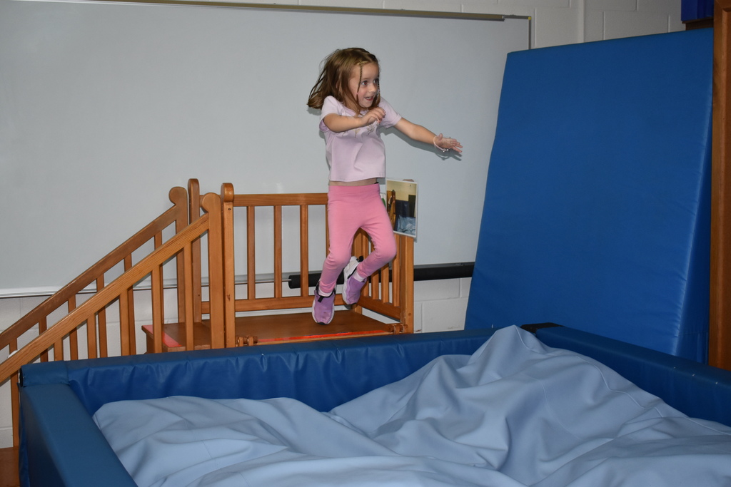 A young student jumping into a soft pit for play