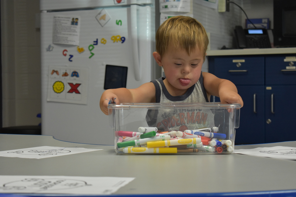 A young student playing with markers at a table