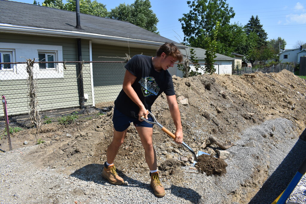 A student tossing a shovel of dirt to represent the ground breaking