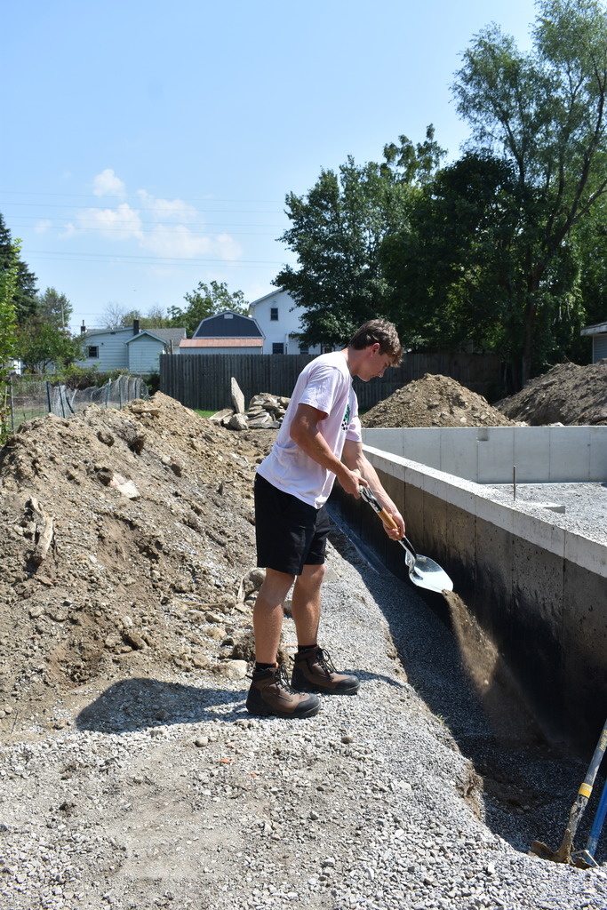 A student tossing some dirt to signify the ground breaking